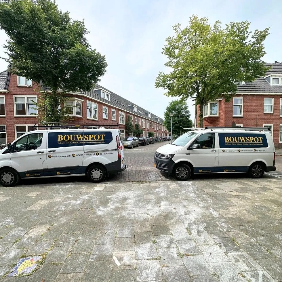 Twee bedrijfsbussen van Bouwspot geparkeerd in een Groningse woonstraat